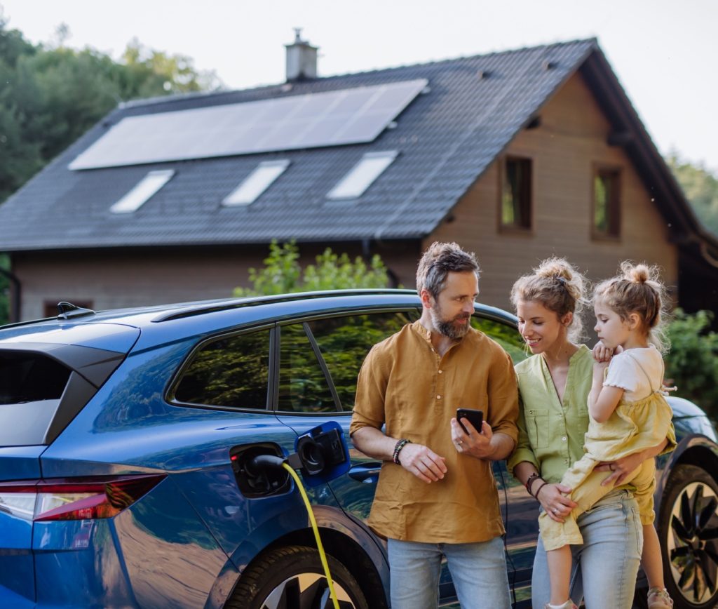 Family charging their electric car with solar panels on roof