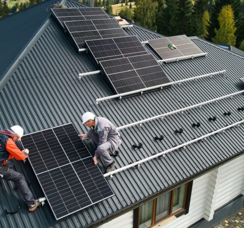 Technicians building solar module on roof of house